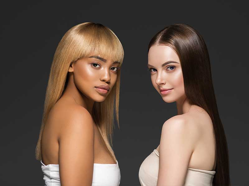 Two Women wearing Wigs to show the Key Differences Between Synthetic and Human Hair Wigs